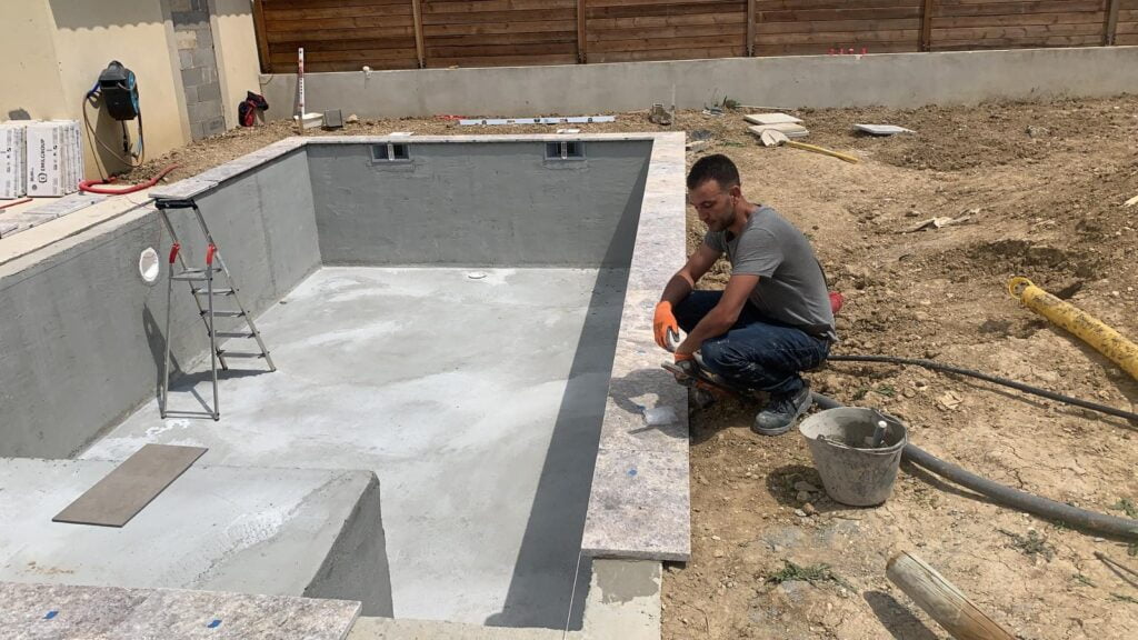 Pose de margelle après mur de soutènement piscine béton