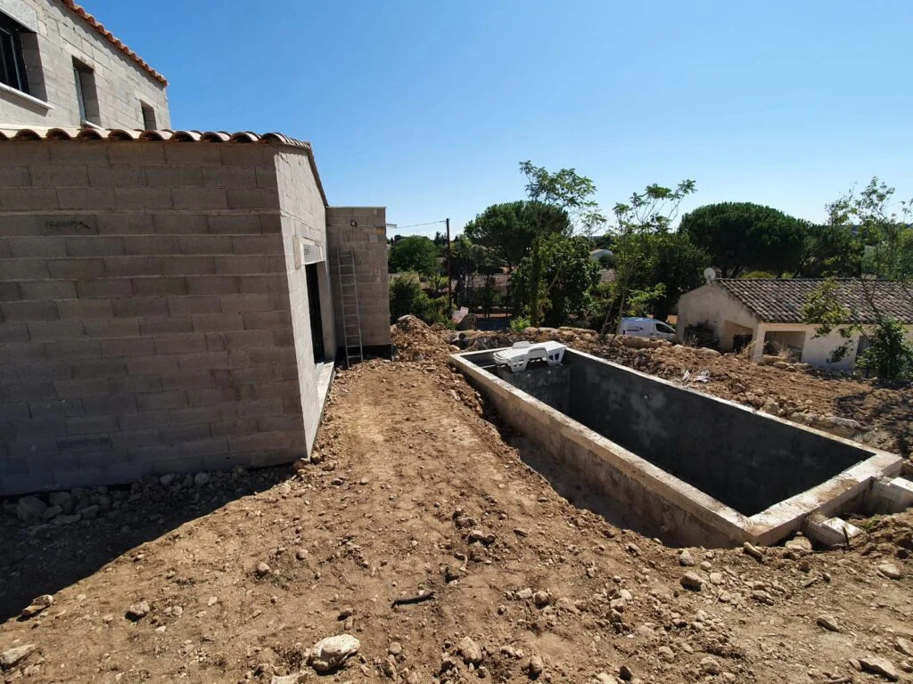 Chantier construction villa R+1 Lambesc en cours — gros œuvre agglo creux, vide sanitaire 1,40 m et terrassement piscine béton 8 × 3 m · Les Maisons Vertes Provençales