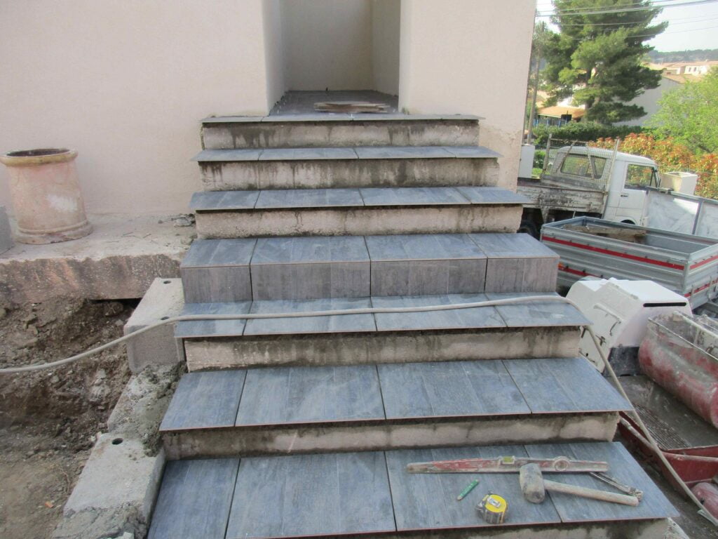 Escalier extérieur habillé en pierre bleue, marches posées et joints en cours de finition