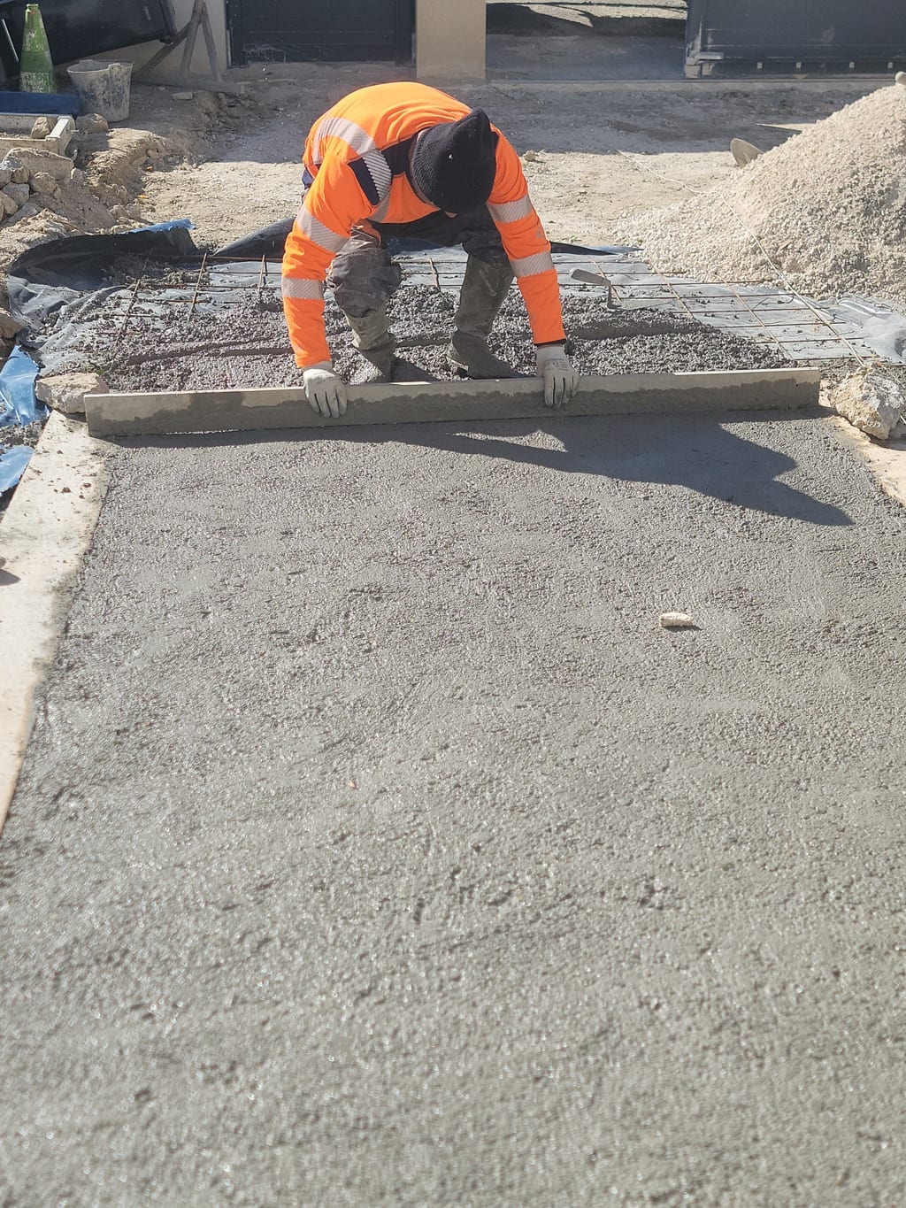 Tirage à la règle du béton frais lors de la réalisation d'une allée carrossable en Provence
