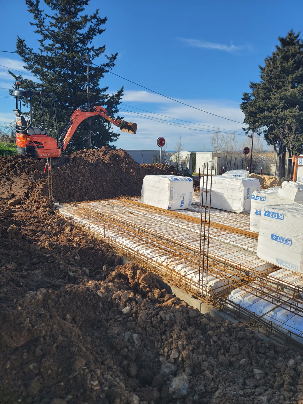 Mini-pelle Kubota positionnant les palettes hourdis
