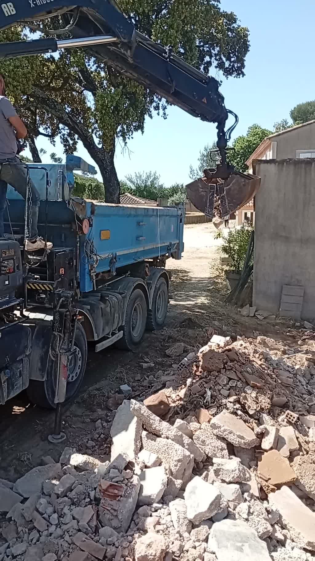 Évacuation des gravats inertes au grappin vers un camion benne sur le chantier de démolition de Vitrolles