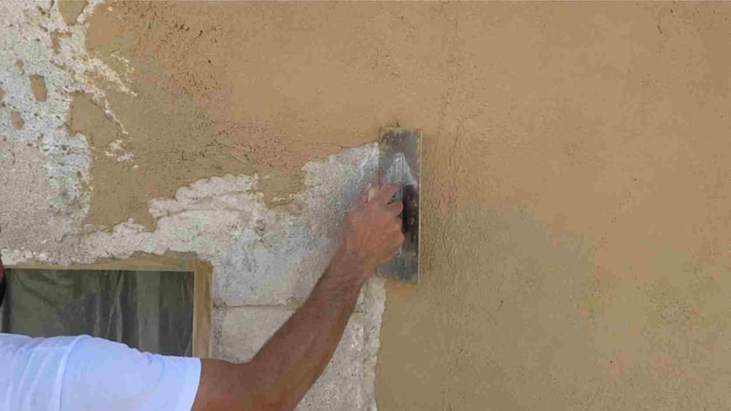 Application manuelle de l'enduit à la chaux aérienne à la taloche inox sur la façade de la bastide, geste artisanal