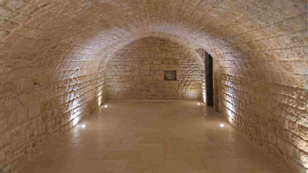 Cave voûtée d'Arles après restauration : voûte en berceau pierre apparente nettoyée, sol pierre, éclairage indirect encastré