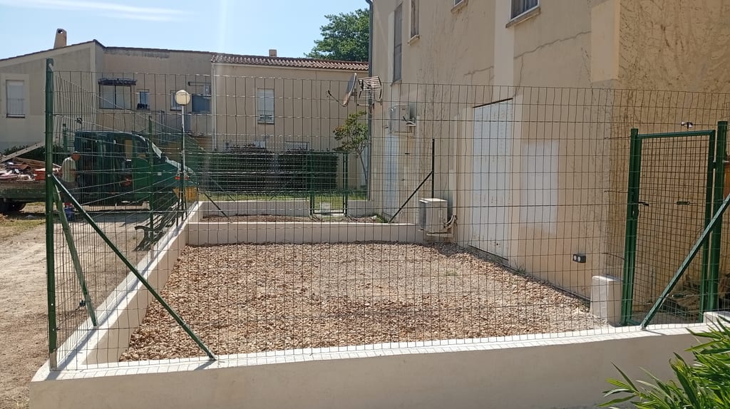 Clôture souple sur muret enduit ton pierre terminée encadrant un jardinet de résidence — Miramas