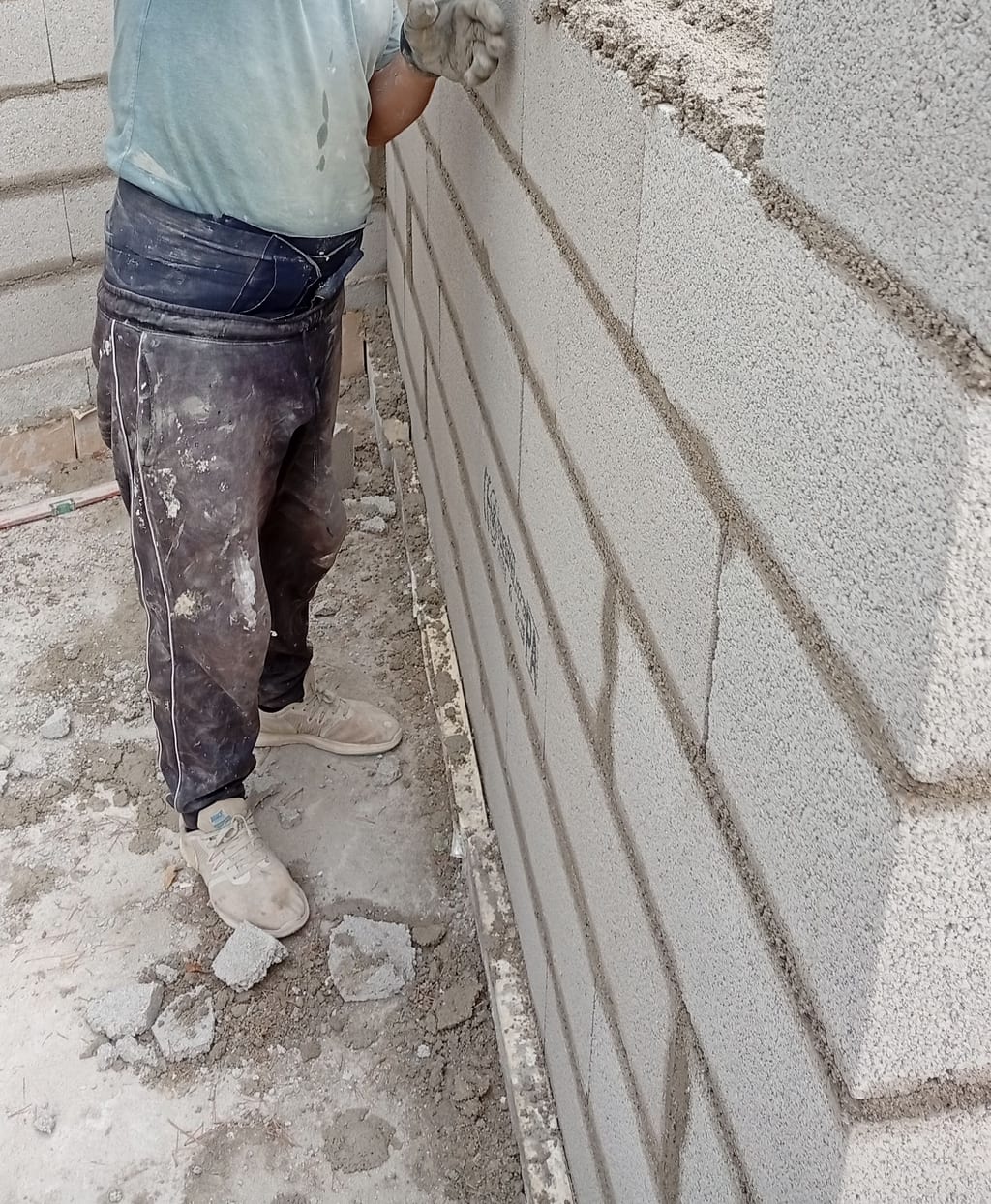 Maçon lissant à la truelle le joint d'un mur en agglo fraîchement monté — extension Marseille 13008